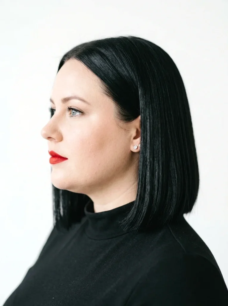 Woman with a round face wearing a sleek straight bob showing clean vertical lines and glossy black shine