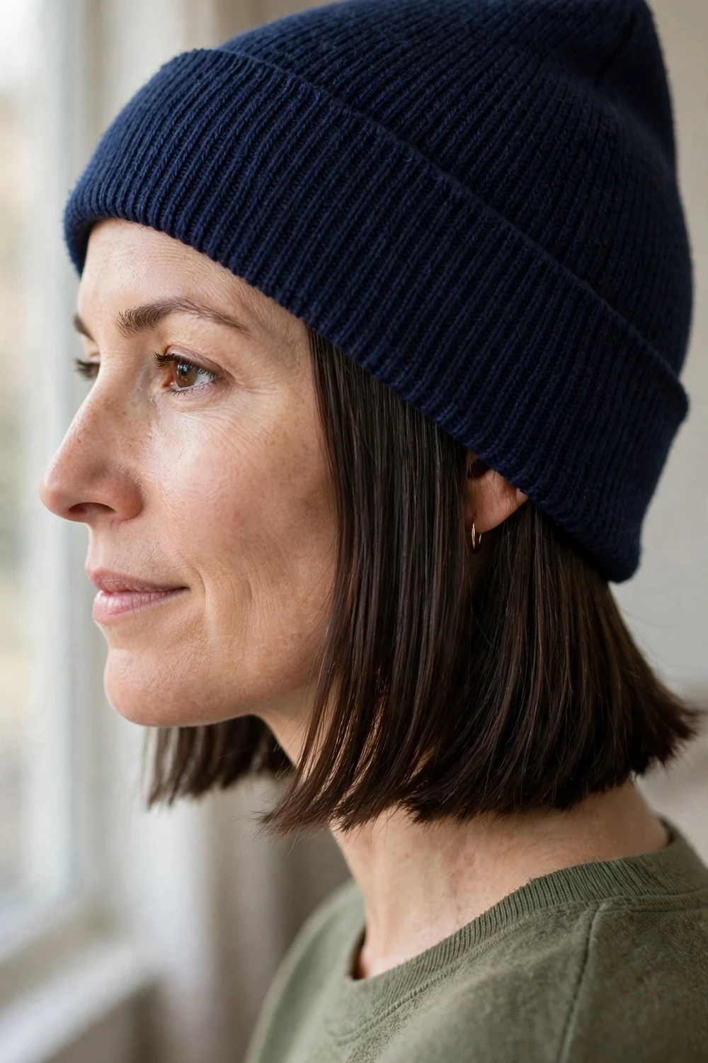 Woman with a sleek chin-length dark bob wearing a navy knit beanie