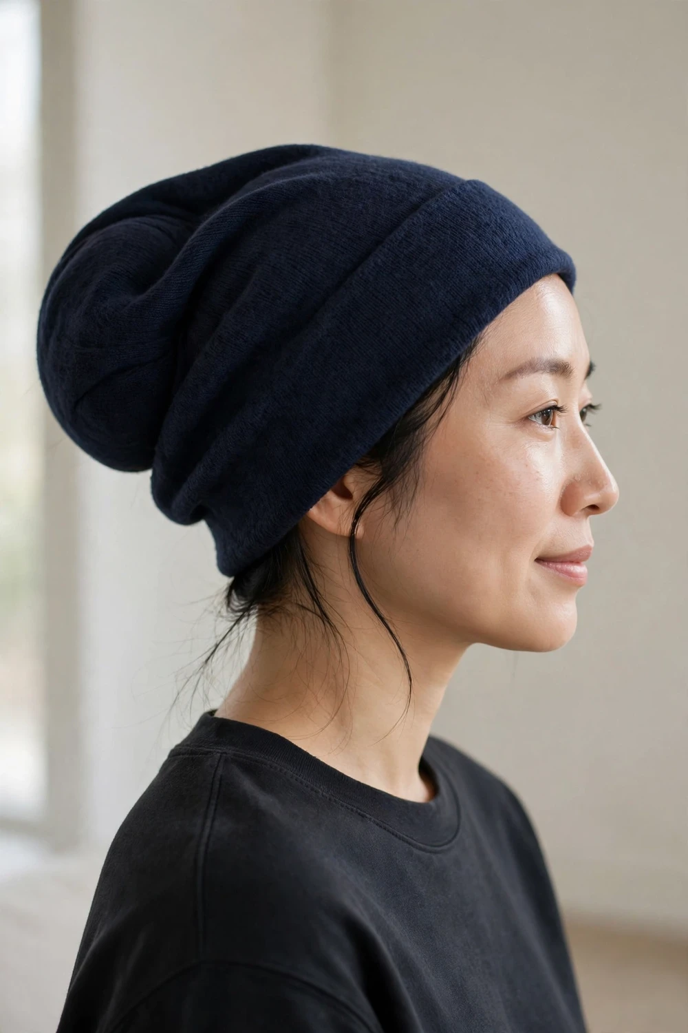 Woman with hair fully tucked in a hidden bun inside a navy slouchy beanie
