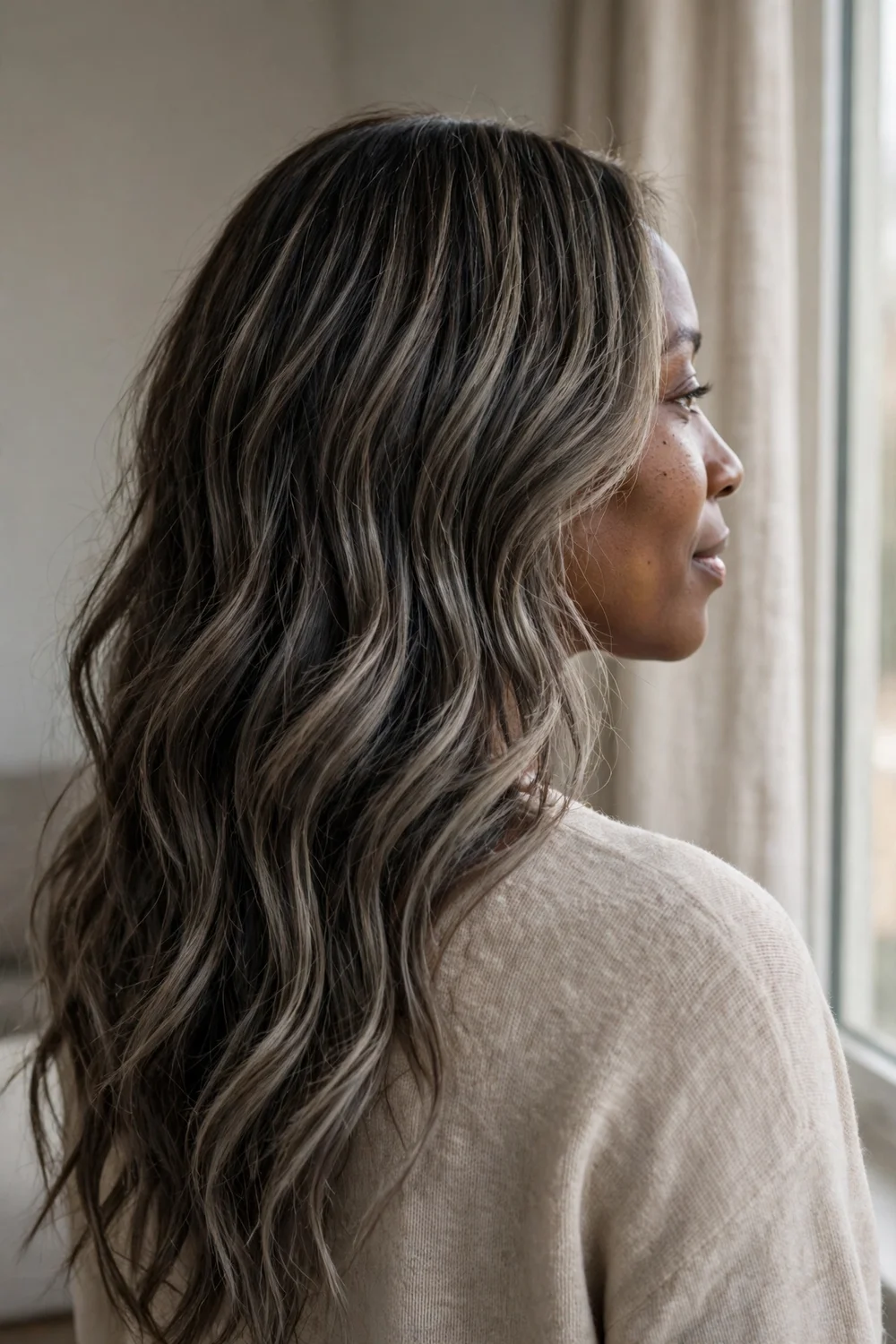 Woman with dark brown wavy hair and cool ash brown balayage