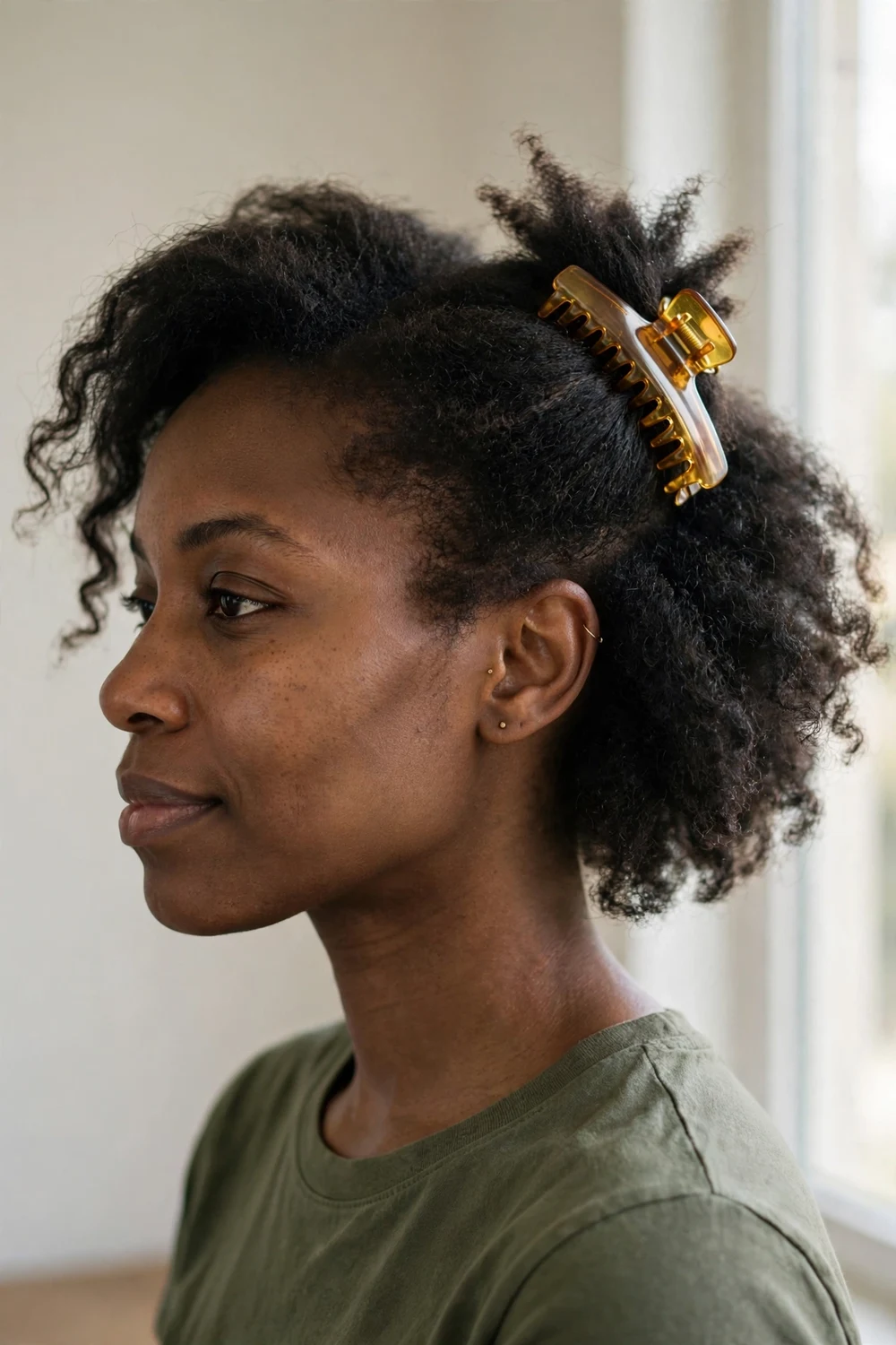 Woman with short natural dark hair with one side pinned up diagonally with a small amber claw clip