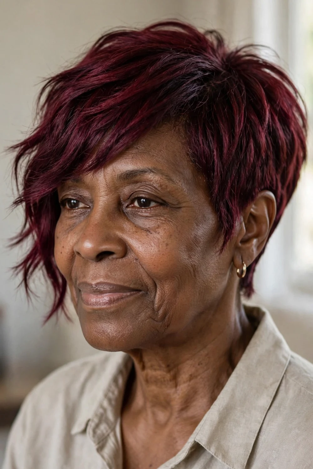 Woman in her 50s with burgundy wine-colored asymmetrical pixie, rich red tones