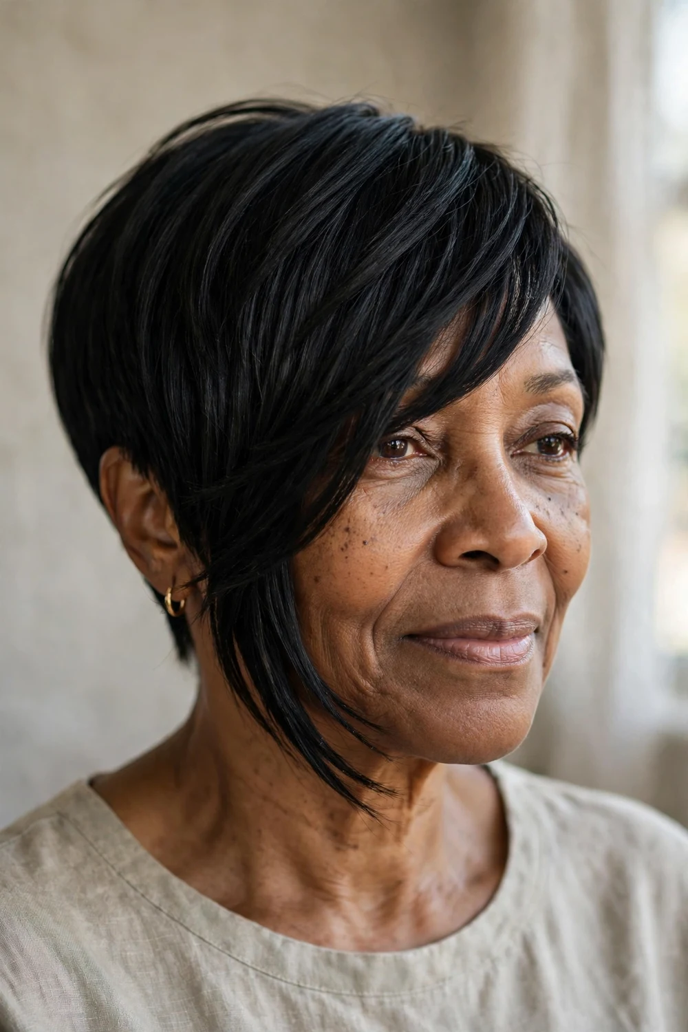 Woman in her 50s with long asymmetrical pixie and side bangs, extended length sweeping past cheek