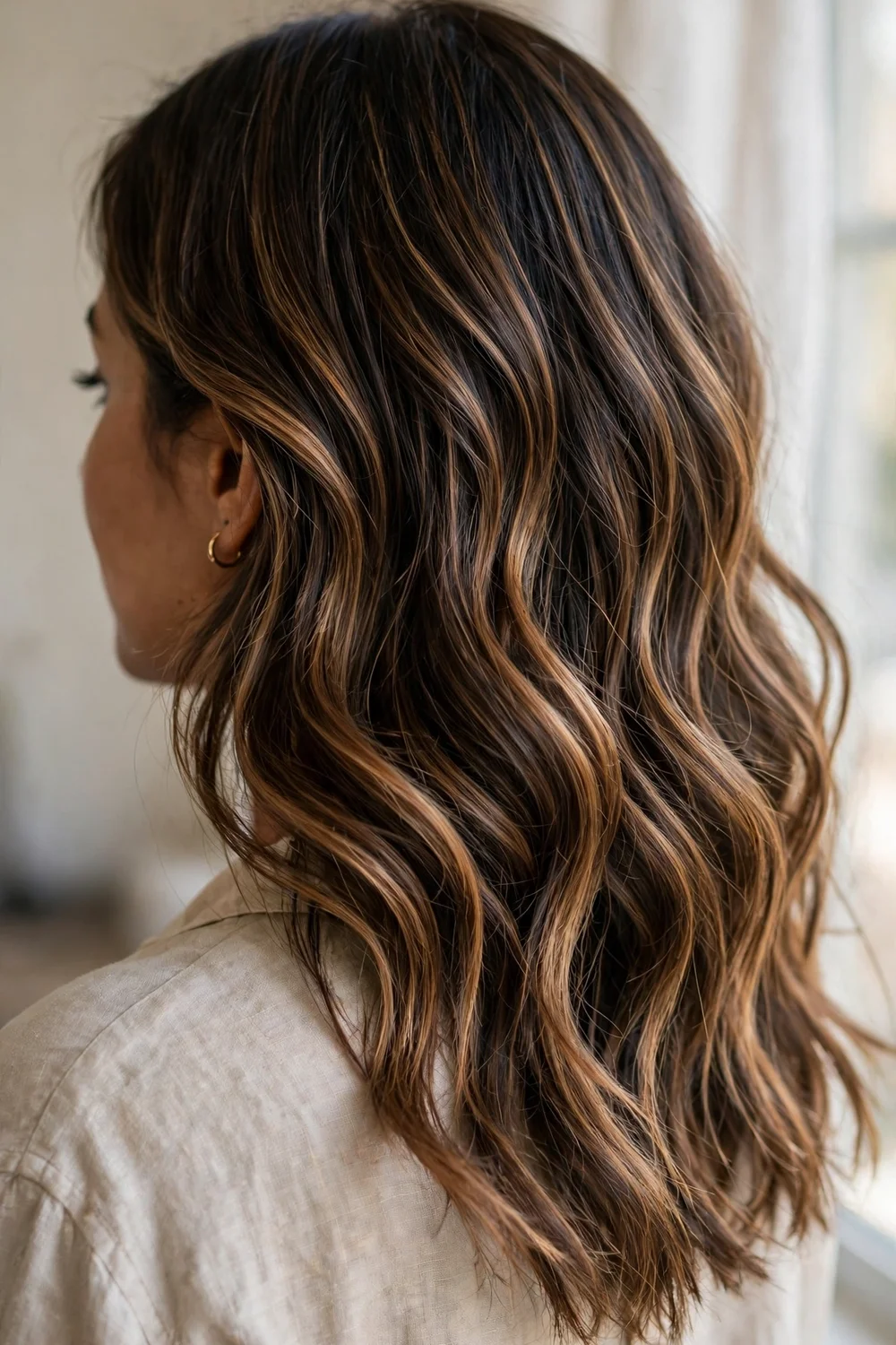 Caramel balayage ribbons through wavy medium-length brunette hair