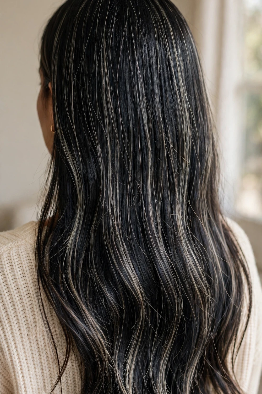 Woman with black hair and ashy babylights with fine cool blonde lights through dark hair