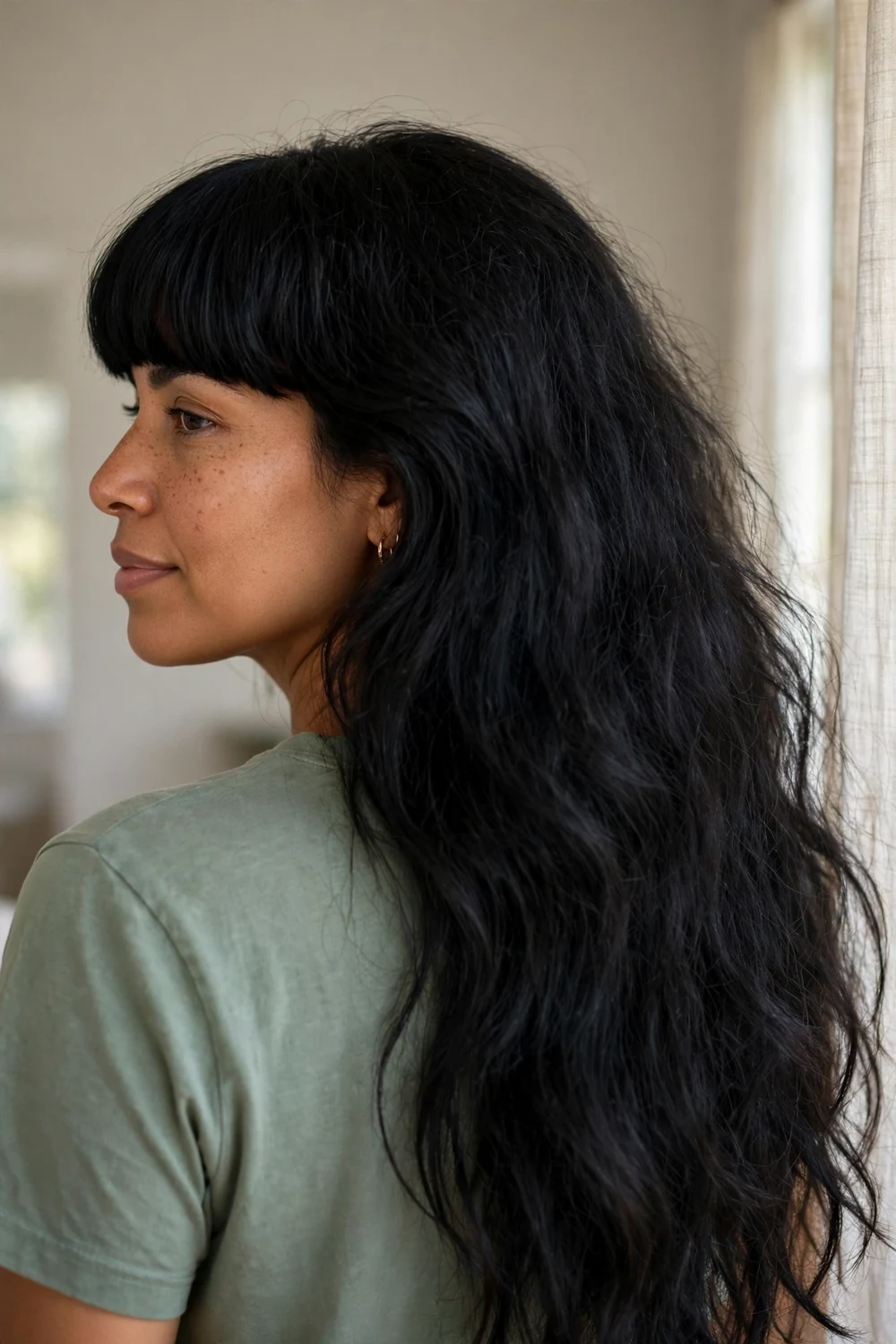 Woman with very thick black hair and blunt bangs, back three-quarter view showing fullness