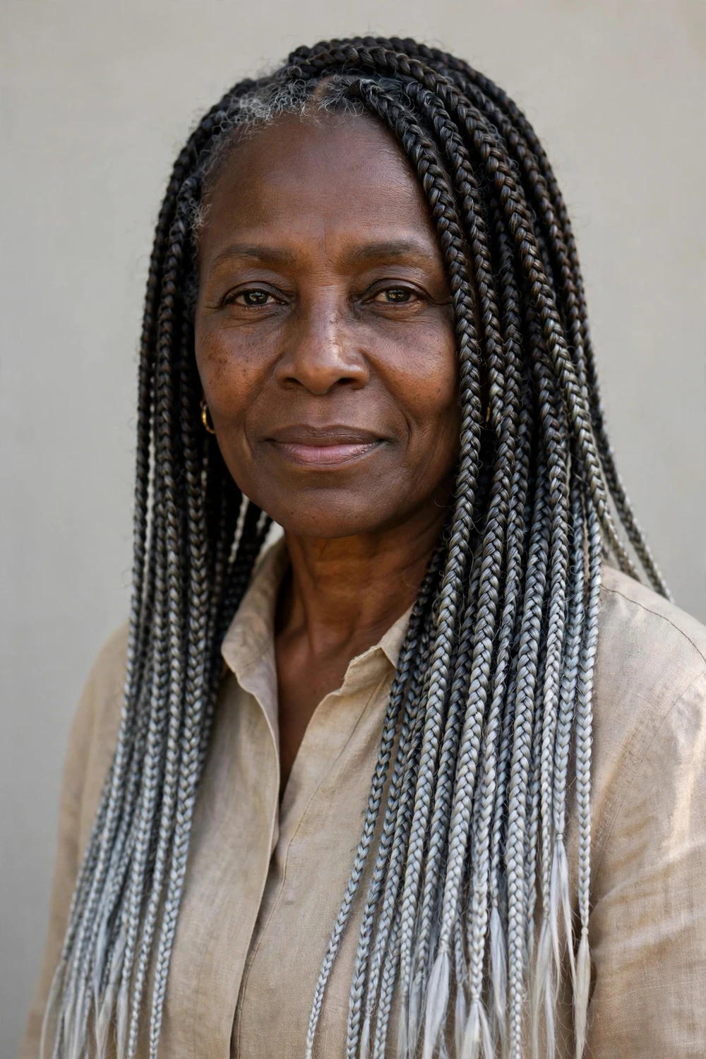 Older Black woman with a high braided topknot of dark braids with silver streaks