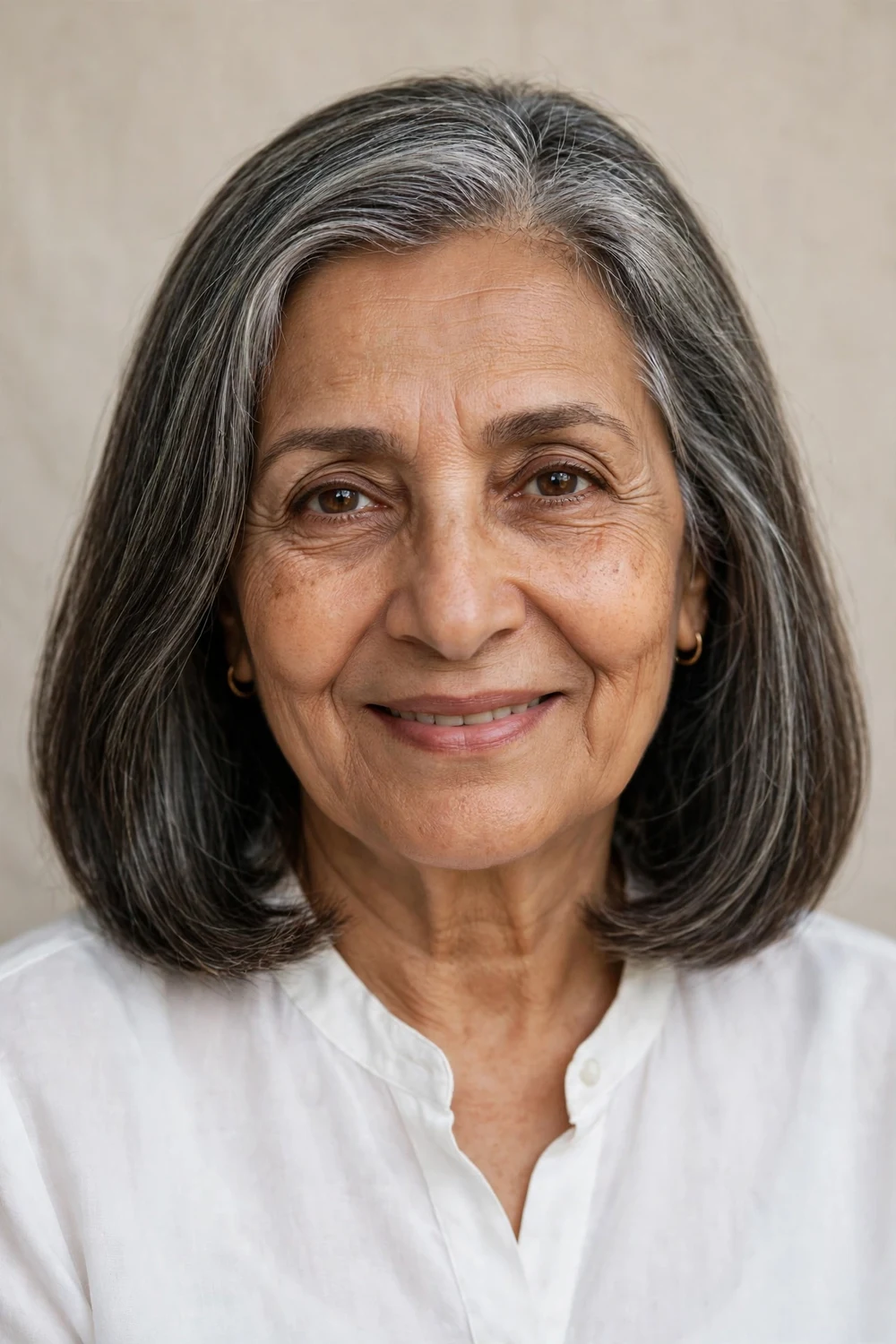 Middle Eastern woman in her early 60s with a sleek shoulder-length lob in salt-and-pepper hair