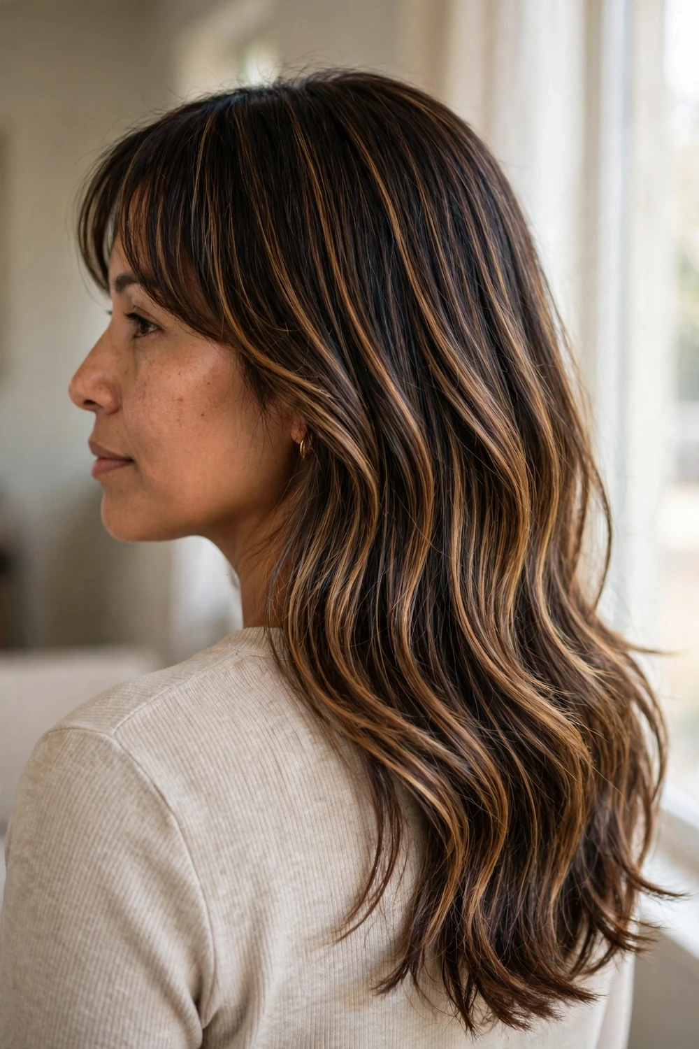 Woman with caramel balayage dimensional layers and curtain bangs