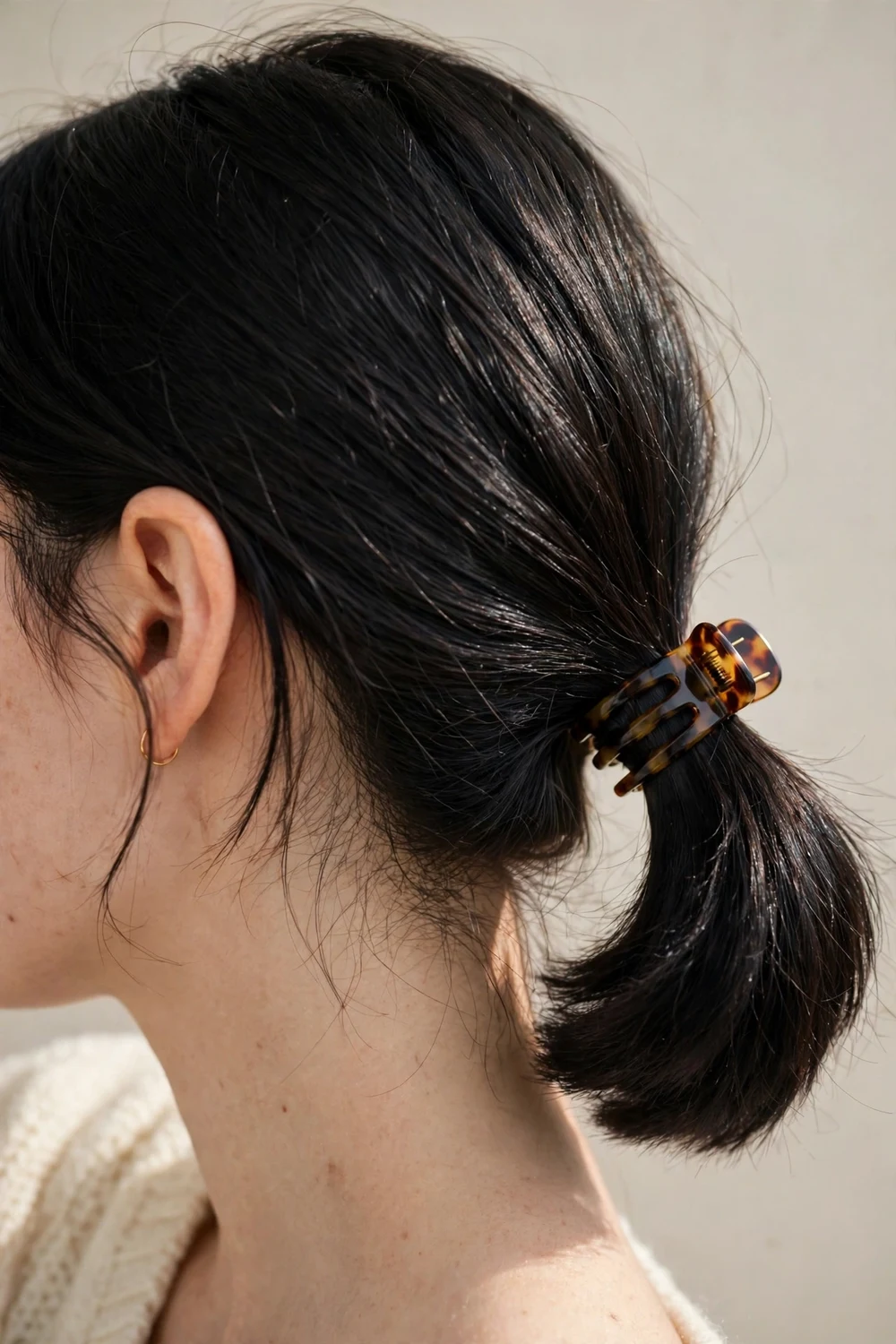 Low ponytail secured with a claw clip on short hair