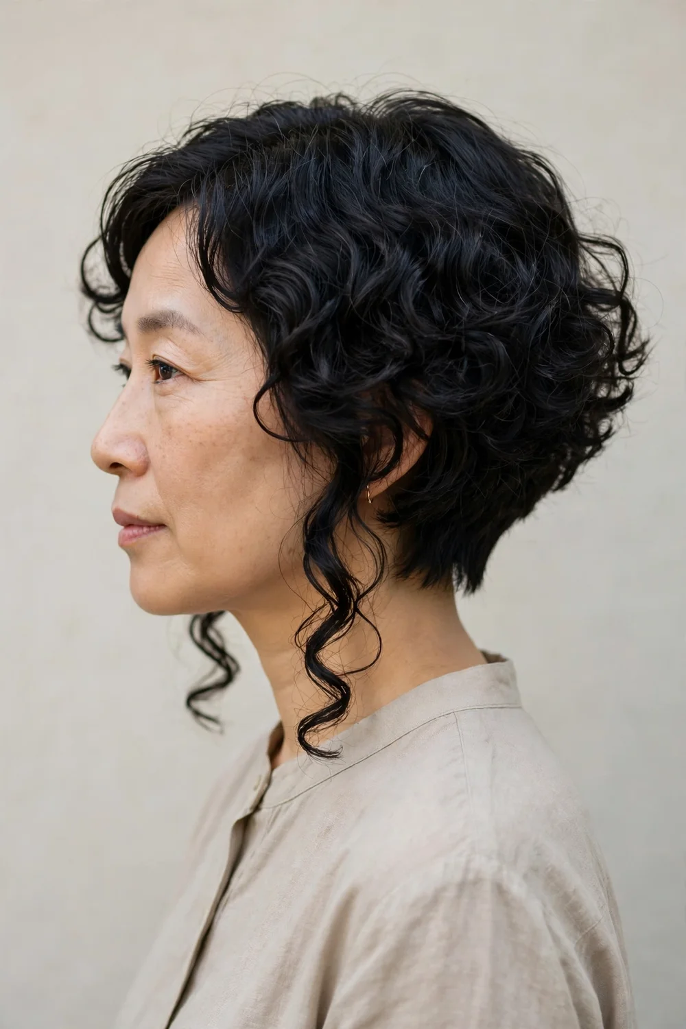 Woman with inverted curly bob, short back and long front