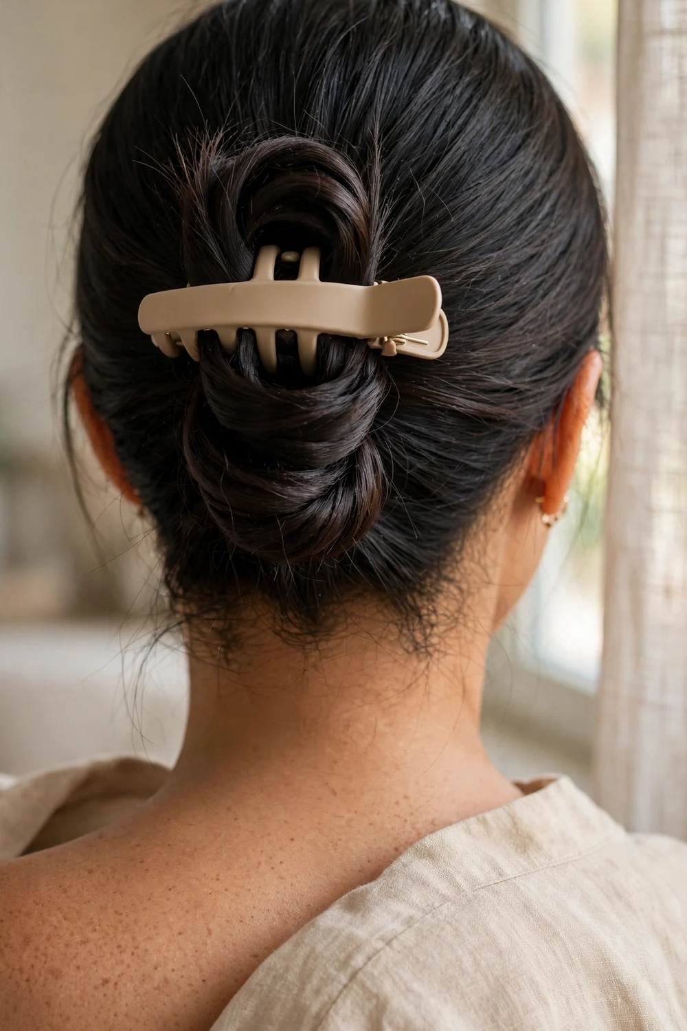 Folded low ponytail secured with beige claw clip on thin fine black hair