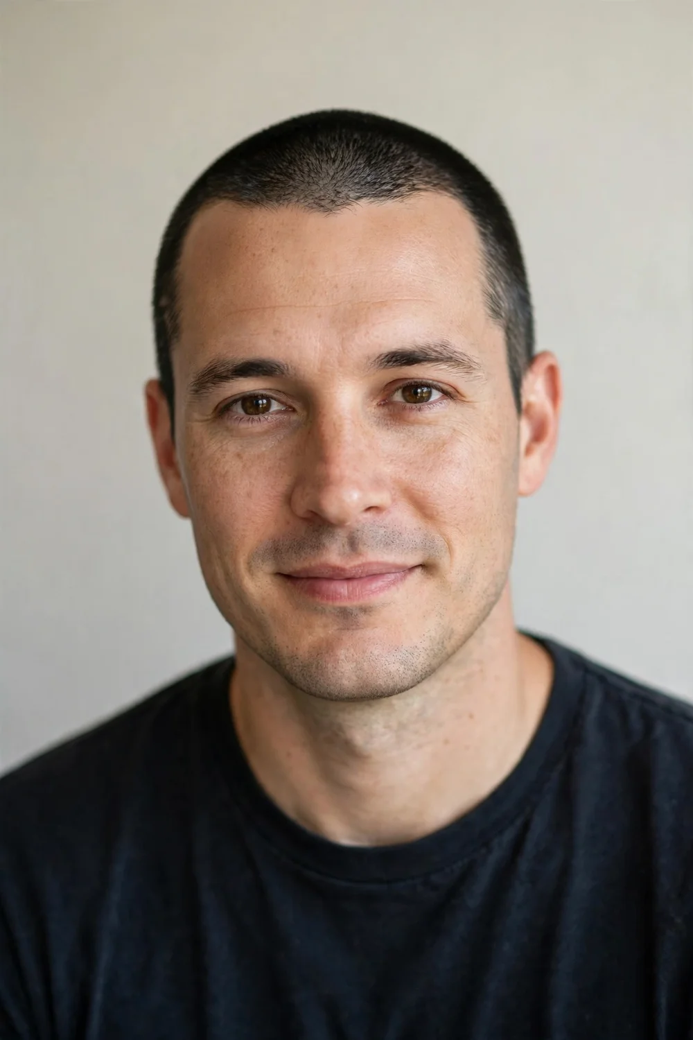 Man in his 30s with a short neat buzz cut and clean natural hairline