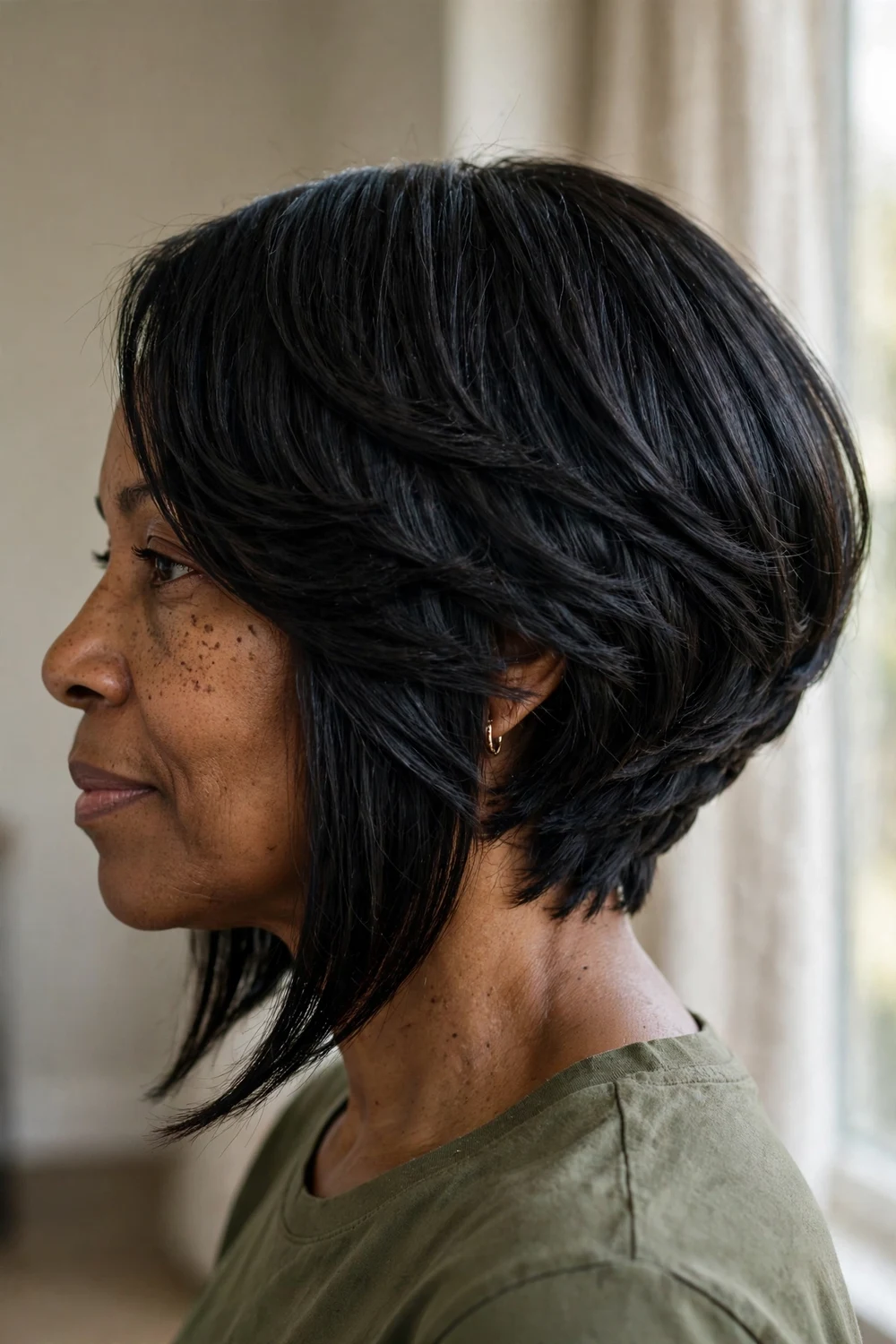 Side view of a layered A-line bob haircut with longer front and shorter back on jet black hair