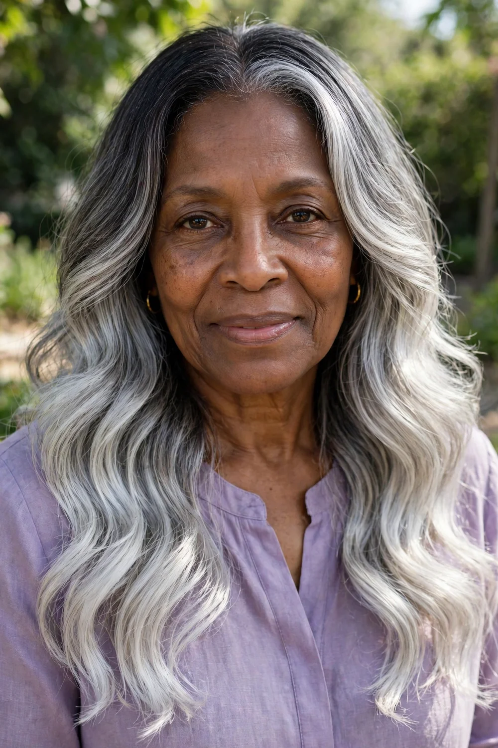 Black woman in her mid 60s with long hair in silver balayage melting from dark roots to silver ends