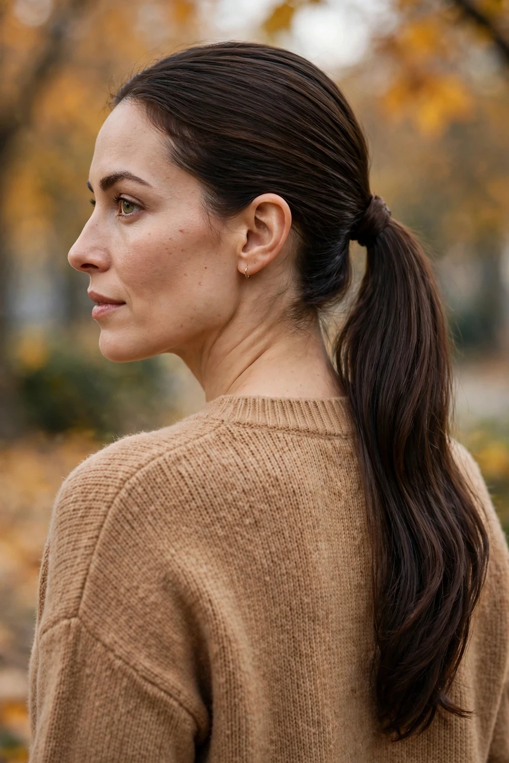 Sleek low ponytail with hidden band, woman with smooth pulled-back hair