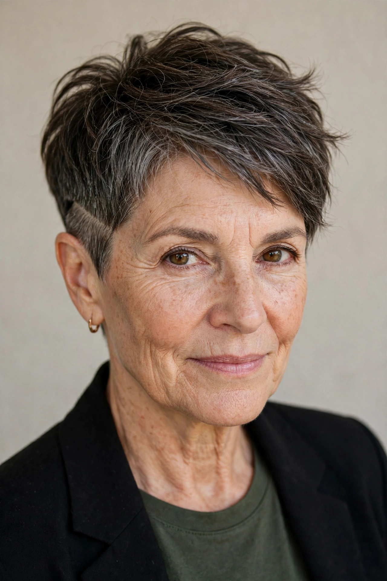 Older woman with a pixie haircut showing a subtle undercut detail above the ear
