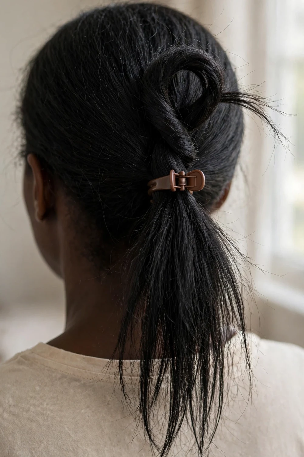 Topsy-tail ponytail with twisted loop and small brown claw clip on thin fine black hair