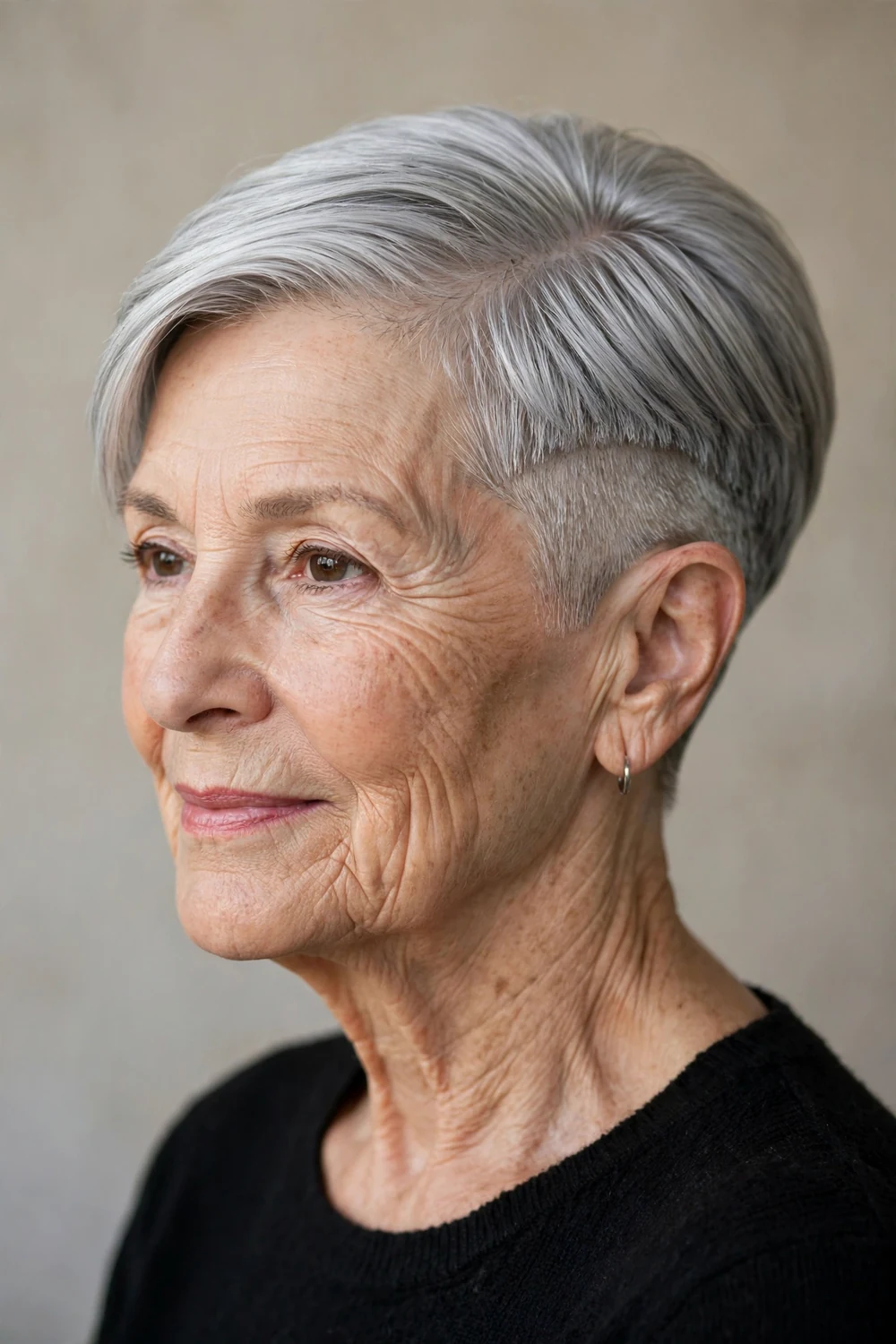 Older woman in her 70s with a sleek silver-gray undercut pixie, polished finish